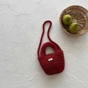 Detailed view of red knitted kids crossbody bag handmade wool purse with cute little tag.