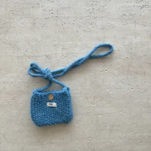 Vue détaillée du sac bandoulière tricoté bleu avec texture en laine fine et joli bouton en bois.