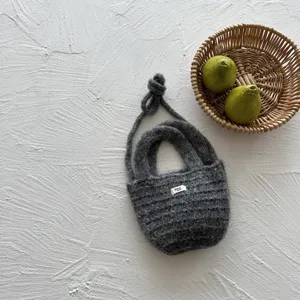 Handmade dark gray knit mini kids bag detail view, soft wool texture with cute tag display.