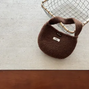 Braune gestrickte Mini Handtasche Detailaufnahme mit Hornknopf und weicher Garnstruktur.