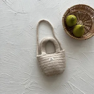 Detailed view of beige handmade knitted kids mini handbag, cute everyday styling accessory.