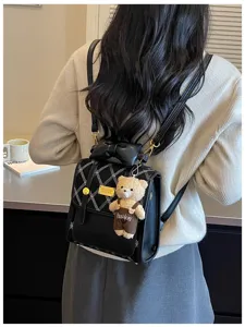 Detailed closeup of women black leather backpack with bow and cute bear pendant charm.