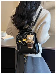 Detail view of black quilted backpack with cute bear pendant, stylish daily commuting bag.