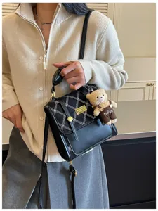 Stylish detail view of the chic black and white plaid handbag with cute bear charm for women.