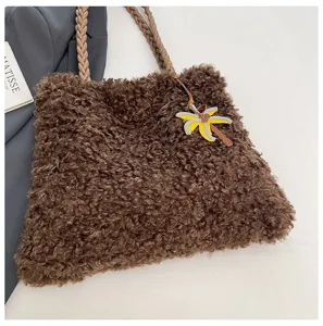 Vista detallada del bolso de felpa marron con asas trenzadas y colgante de palma elegante.