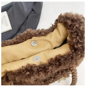 Primer plano detallado de un elegante bolso tote marrón de borreguito esponjoso con cierre magnético.