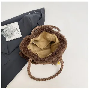Vista detallada del bolso tote de felpa marrón suave con asa trenzada y bolsillo.