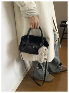 Detail view of stylish black fluffy plush crossbody shoulder pillow bag with cute bunny charm.