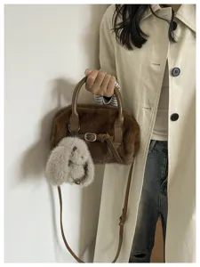 Detailed view of the winter plush handbag with fluffy charm and buckle strap design.