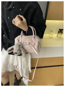 Plush pillow shoulder bag detail shot in soft pink faux fur with bunny pendant charm.