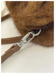 Close-up view of fluffy plush handbag strap connection and silver metal hardware clasp detail.