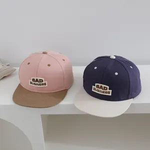 Primer plano de gorra de béisbol infantil en contraste con visera plana y bordado.