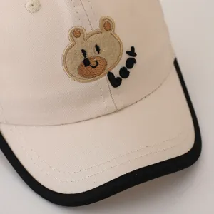 Infant baseball cap with cute bear embroidery, beige cotton kids sun hat with black brim.