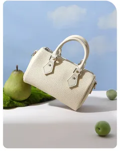 Detailed view of cream white mini leather Boston bag styled with artistic fruit props.