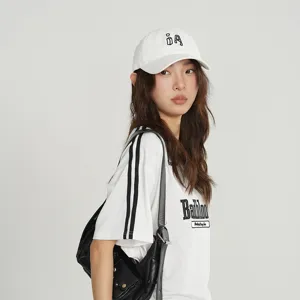 Detailed shot of a stylish white baseball cap with black letters, worn by model with mesh t-shirt.