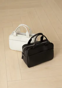 Detailed view of stylish leather bowling bags in black and white, showcasing texture and hardware.