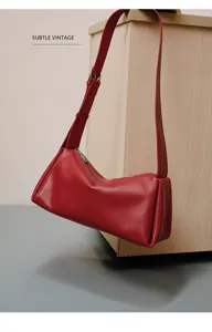 Detalle de bolso de hombro de cuero rojo con textura premium y cremallera metálica.