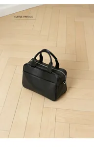 Detail view of a chic black leather bowling bag, stylish top handle design for daily commuting.