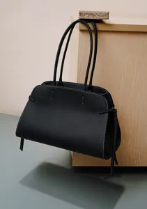 Minimalist black leather tote bag with white stitching detail, premium women's shoulder handbag.