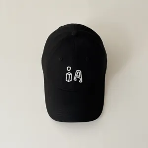 Close-up detail of a trendy black cotton baseball cap with white embroidery lettering, front view.