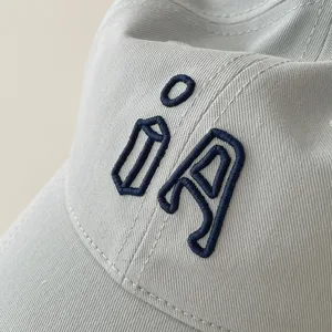 Close-up detail of children's baseball cap, showing dark blue embroidery texture and soft fabric.