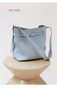 Light blue leather bucket bag with classic turn-lock strap closure and adjustable shoulder strap.