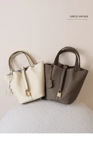 Detalle de bolso cubo de cuero genuino con textura suave, candado metálico y estilo minimalista.