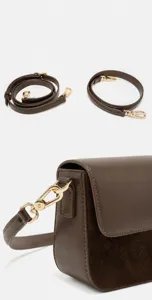 Détail de sac à main en cuir marron avec sangles réglables et quincaillerie dorée élégante.