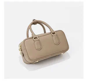 Detailed view of the taupe leather bowling bag showing premium hardware and fine stitching texture.