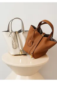 Bolso cubo de cuero genuino con asa y cerradura de metal para el uso diario casual.