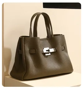 Gros plan sur le sac cabas en cuir vert olive avec fermoir tourniquet et poignées.