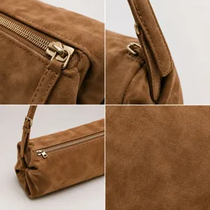 Bolso de hombro cilíndrico de ante marrón con cremallera metálica y correa.