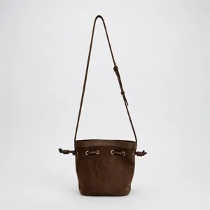 Brown genuine leather bucket bag with adjustable crossbody strap and stylish drawstring design.