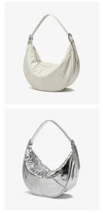 Detailed view of the genuine leather crescent shoulder bag in cream and metallic silver finishes.