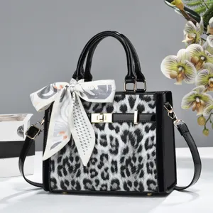 Sac à main léopard noir et blanc en cuir verni, avec foulard nœud élégant et bandoulière chic.
