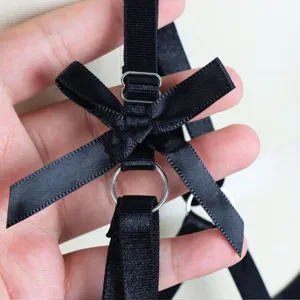 Black lingerie harness detail close-up featuring satin bow and metal ring adjustment straps.