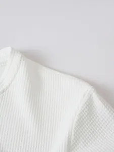 Close-up detail of white waffle knit long sleeve shirt collar, textured fabric texture.