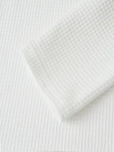 Close-up detail of white waffle knit fabric, showing texture for men's casual sleeve top.