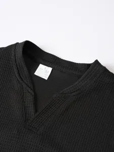 Detail of mens black waffle knit long sleeve V-neck t-shirt collar showing fabric texture.