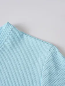 Detailed close-up view of men's light blue waffle knit long sleeve t-shirt fabric.