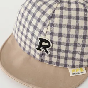 Close-up detail of infant plaid baseball cap with soft khaki brim and cute embroidered letter.