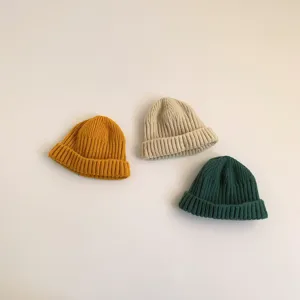 Detailed view of three colorful knitted beanies in yellow, beige and green, soft texture.