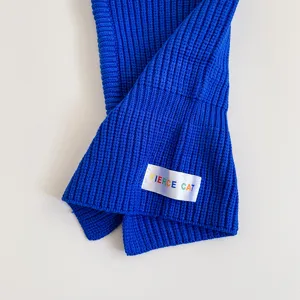 Royal blue knit scarf detail shot showing soft textured fabric and woven label closeup