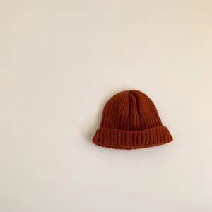 Detailed view of cozy children's knit beanie in warm rust orange, simple and soft texture.