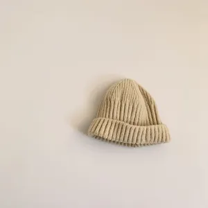 Close-up detail of soft beige knit baby beanie hat, warm winter accessory for kids.
