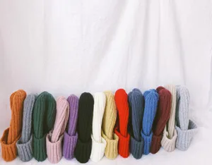 Detailed view of colorful knitted beanies lined up neatly, showing diverse solid colors.