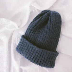 Close-up detail of a soft knitted beanie cap, solid navy blue color, ribbed winter warm hat.