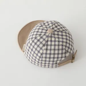 Close up of infant plaid baseball hat with soft brim, showing fabric texture and side tag.