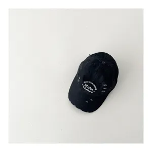Close-up detail of children retro distressed black baseball cap with white letter embroidery.