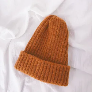Close-up detail of soft warm winter knitted beanie hat in orange, cozy texture for kids.